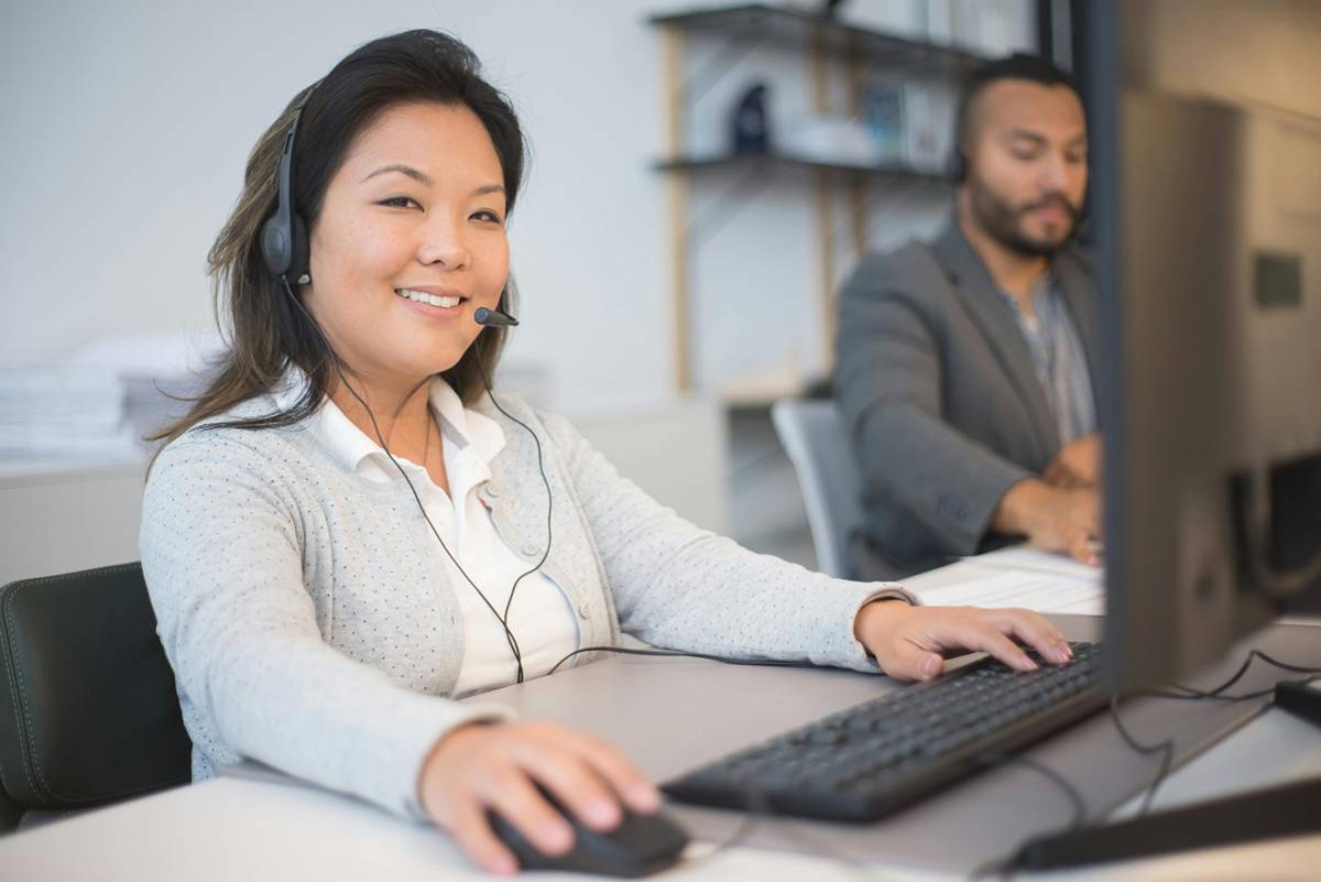 Woman accepting a call while smiling while her colleague is taking down notes from a call